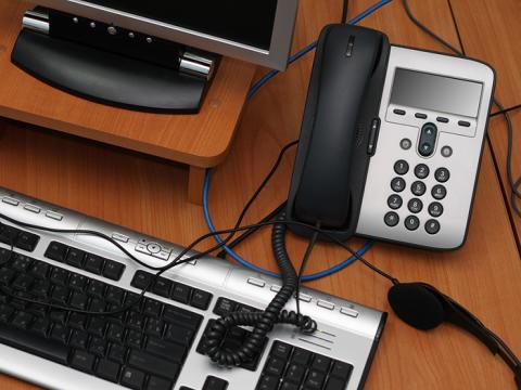 desk with phone, keyboard, computer screen
