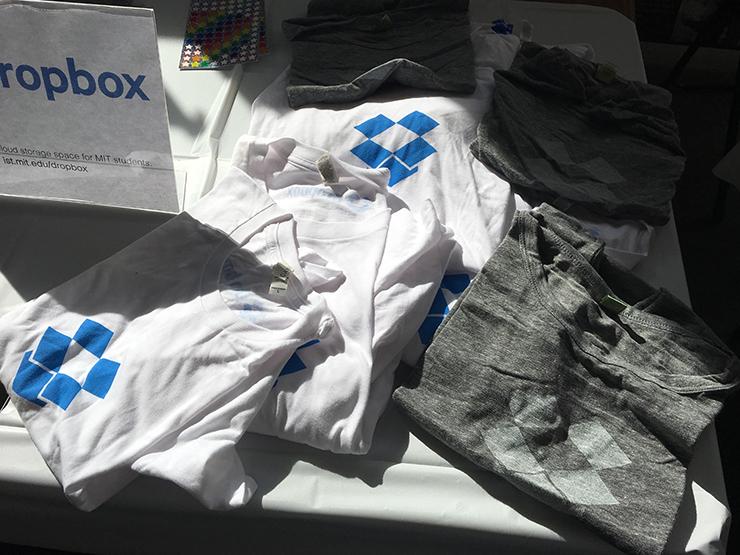 Several white and gray t-shirts on a table with the Dropbox logo on a table.