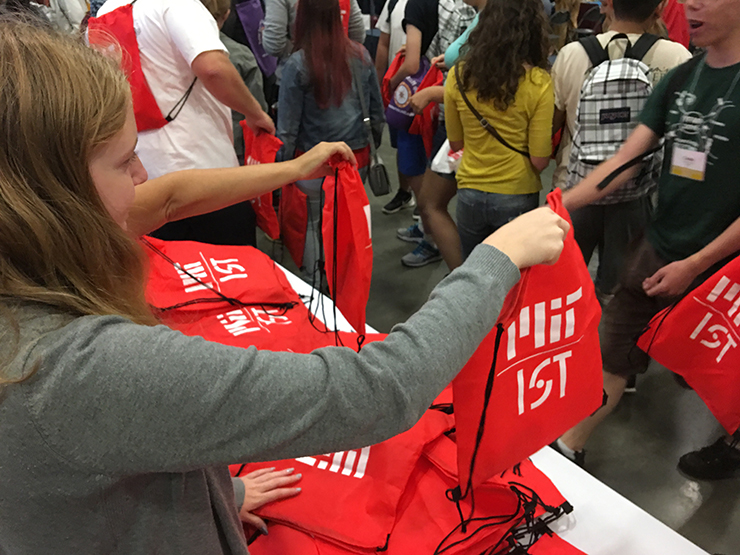 Woman handing out a bag that says MIT IS&T to students