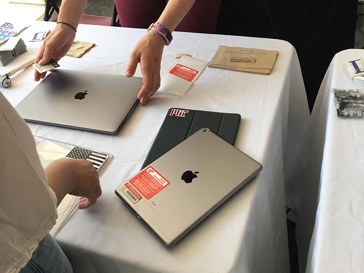 A laptop and tablet being tagged with STOP Theft tags